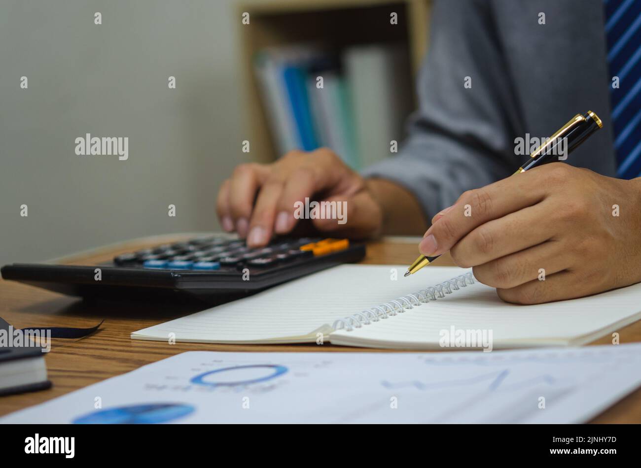 Homme main tenant stylo écriture livre analyse d'investissement d'affaires graphique rapport sur le tableau. Banque D'Images