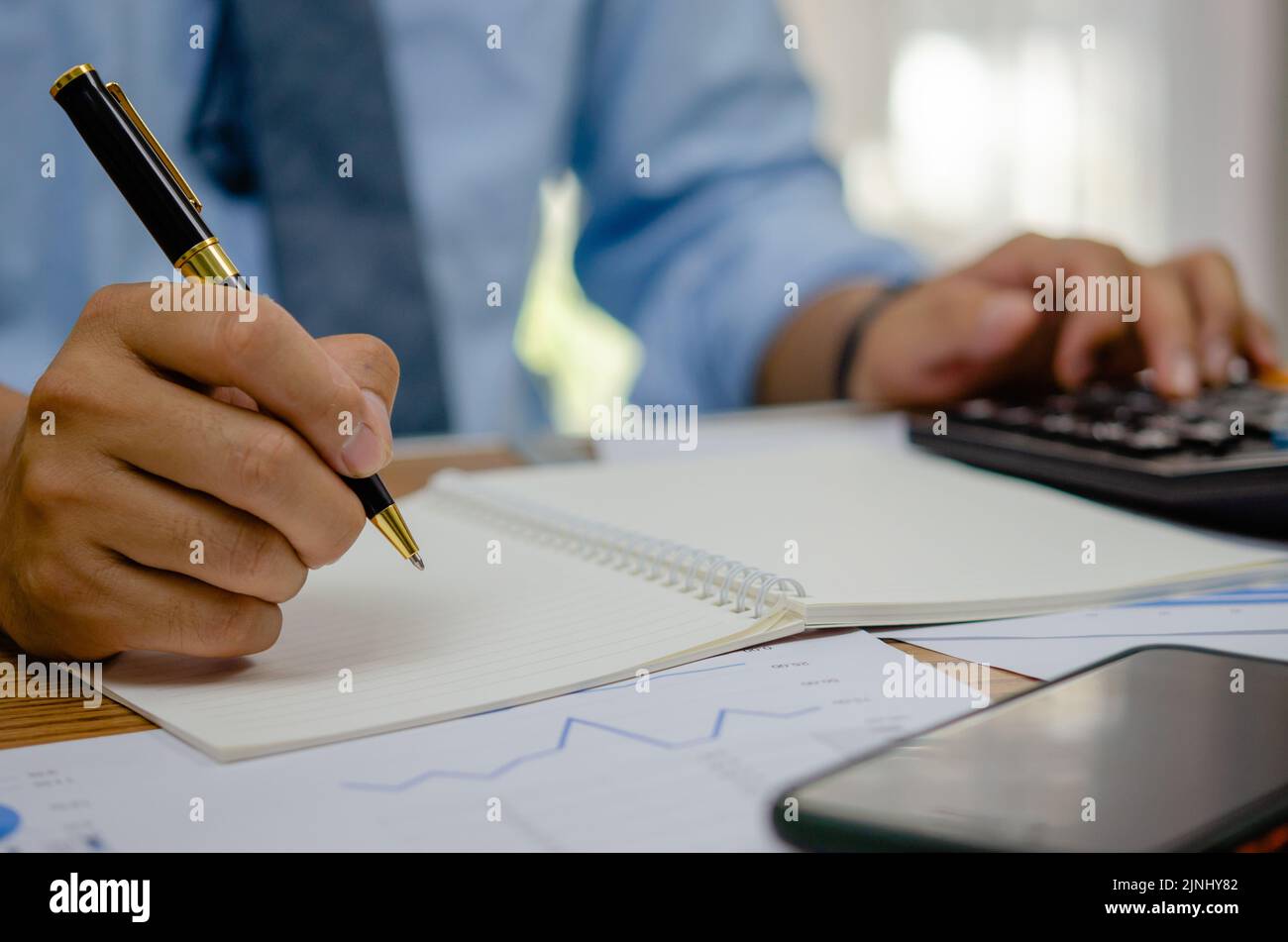 Homme main tenant stylo écriture livre analyse d'investissement d'affaires graphique rapport sur le tableau. Banque D'Images
