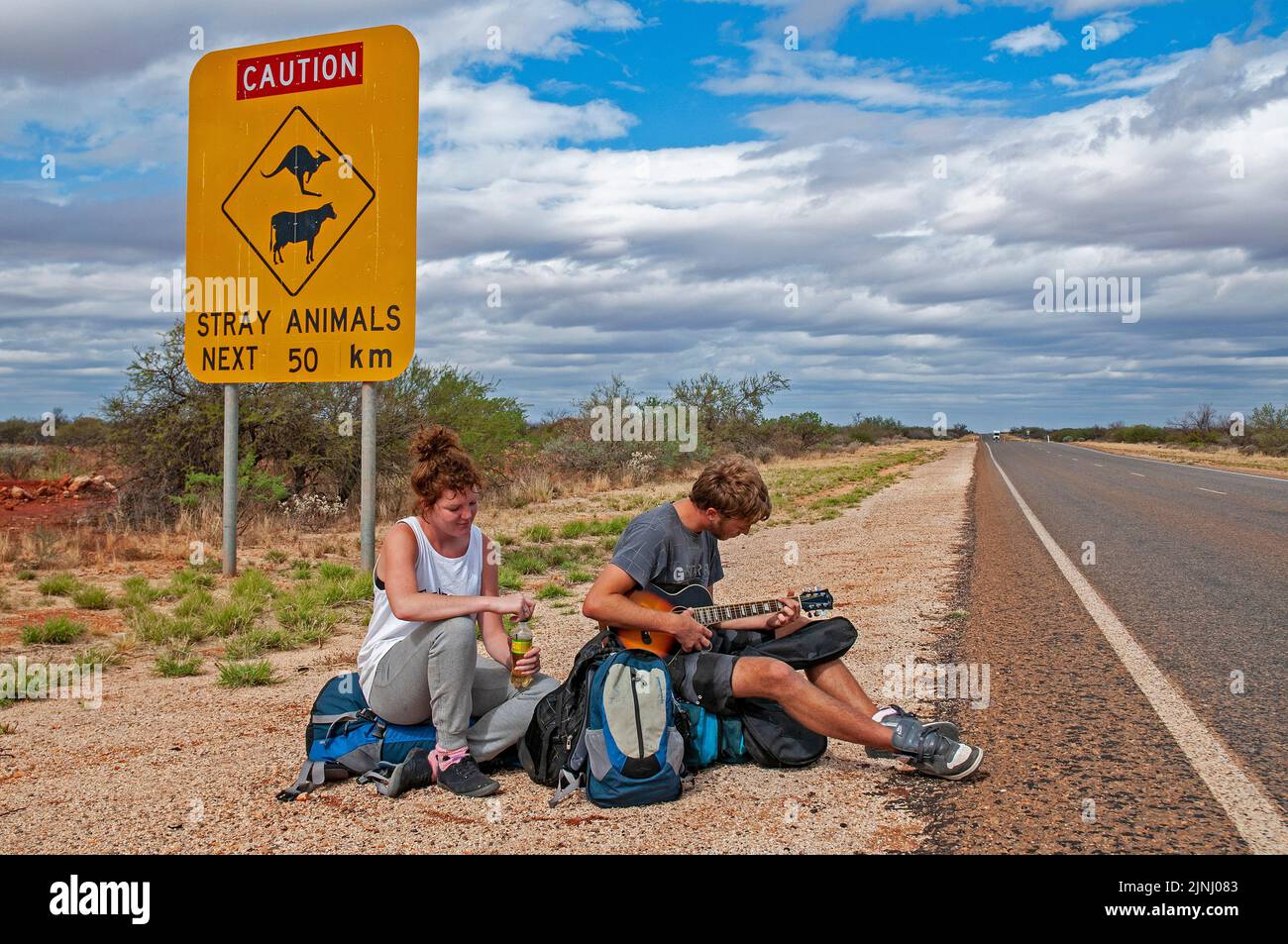 Un couple de jeunes routards britanniques attendant un ascenseur sur l'autoroute près de Monkey Mia en Australie occidentale Banque D'Images