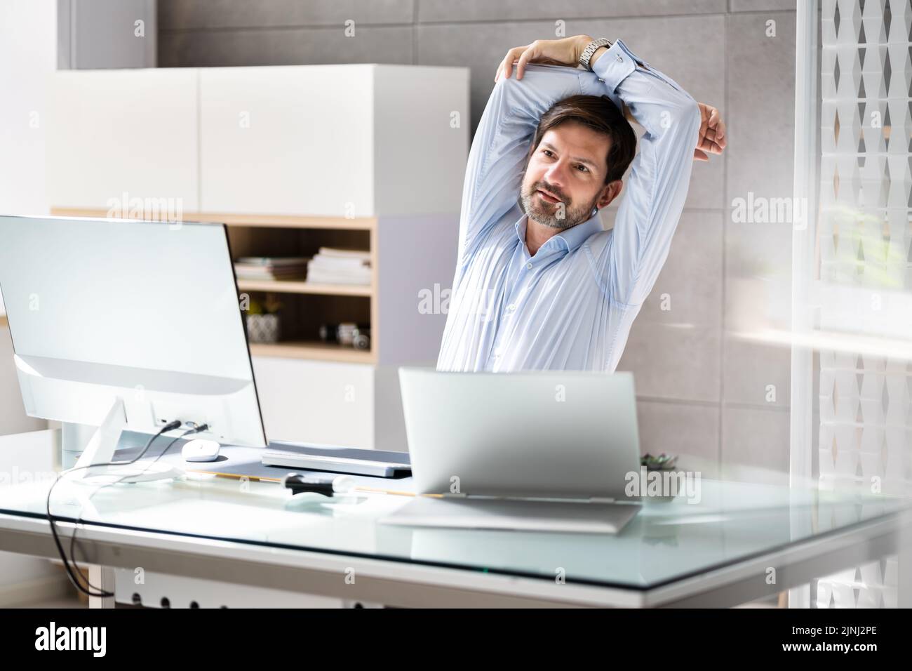 Vue arrière d'un homme d'affaires s'étend ses bras In Office Banque D'Images