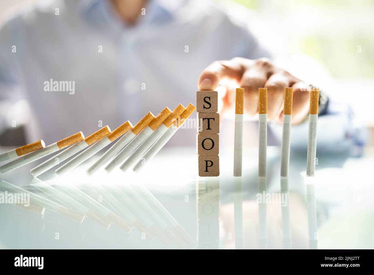 Homme empêchant la cigarette de tomber sur le bureau avec des blocs de bois Banque D'Images