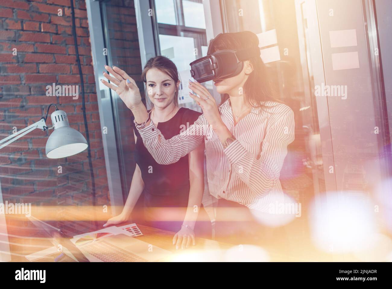 Les travailleuses de bureau s'amusent au travail en regardant 3D vidéos dans des lunettes VR, une femme touchant quelque chose en train de vivre la réalité virtuelle. Banque D'Images