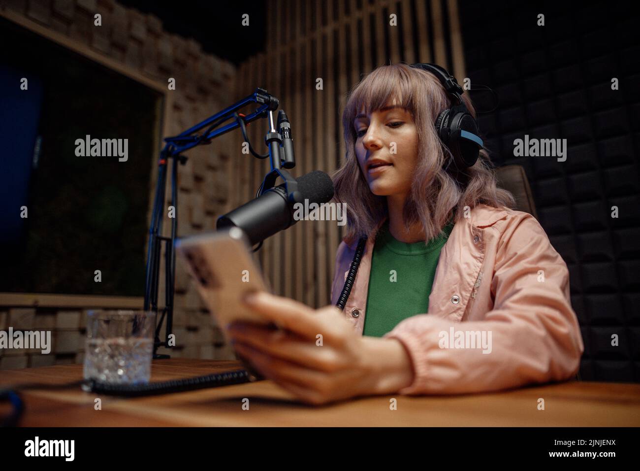 Une jeune femme hôte parle au microphone et interroge un homme pour un podcast radio, à l'aide d'un smartphone. Banque D'Images