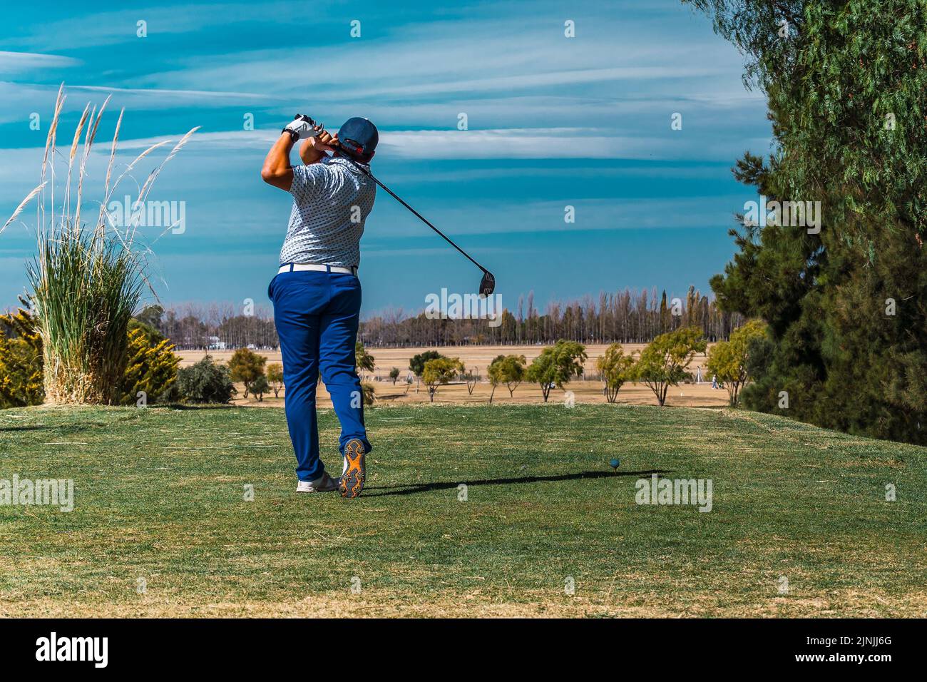 Un homme vu de derrière, jouant au golf sur un terrain vert Banque D'Images