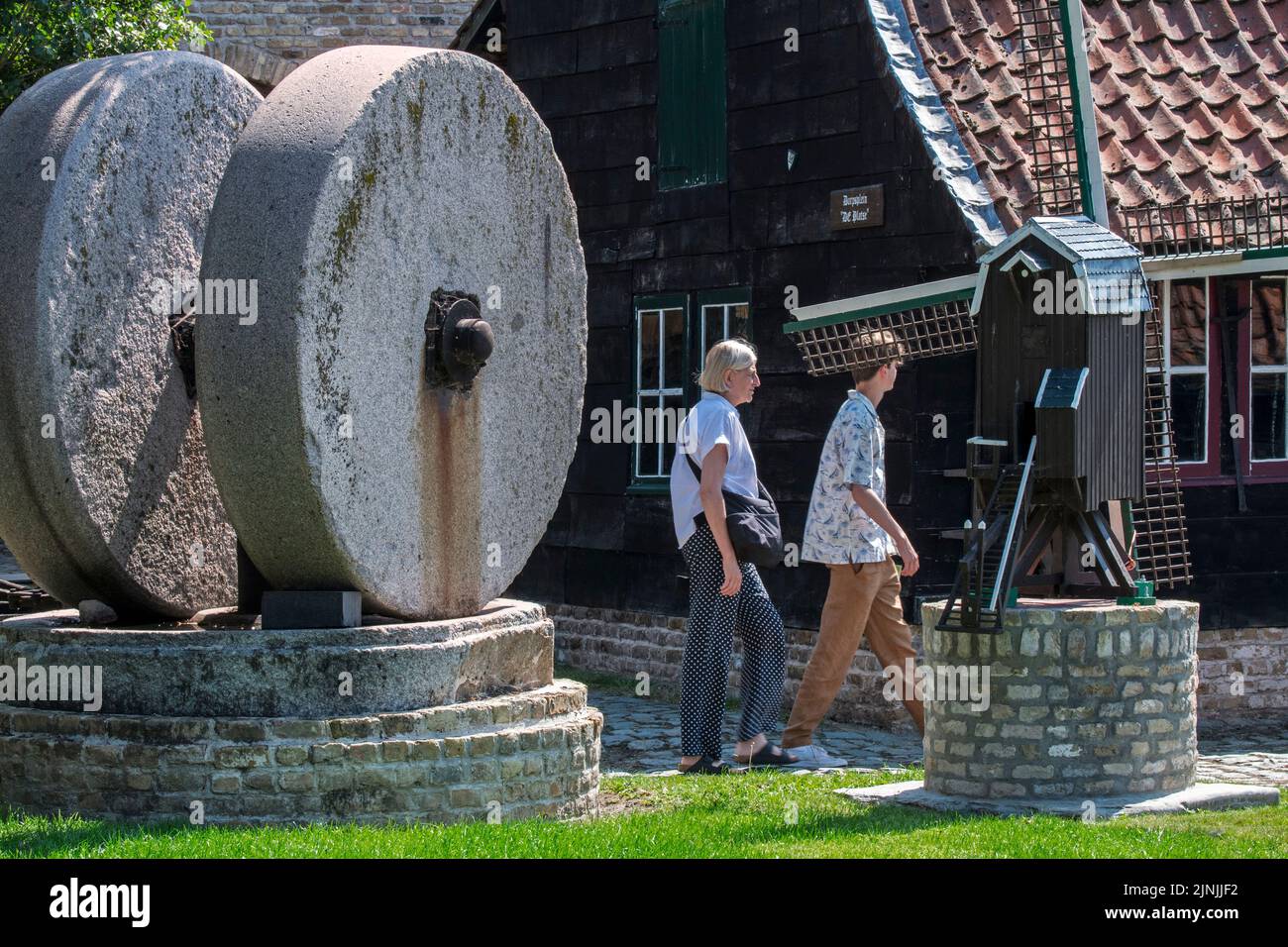 Pierres à moulin / pierres à moulin et touristes visitant le musée en plein air Bachten de Kupe, Izenberge, Flandre Occidentale, Belgique Banque D'Images
