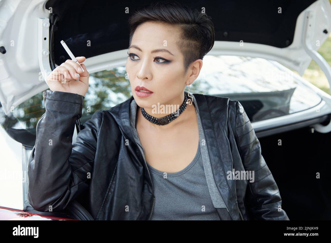 Portrait de la belle jeune femme asiatique édgée fumant de la cigarette Banque D'Images