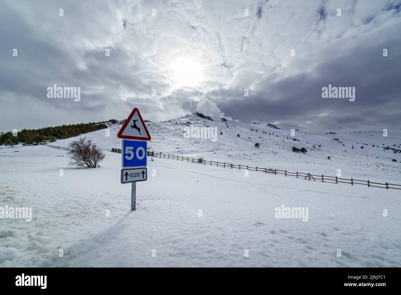 Paysage hivernal enneigé avec signalisation routière couverte de neige et de soleil dans le ciel. Banque D'Images