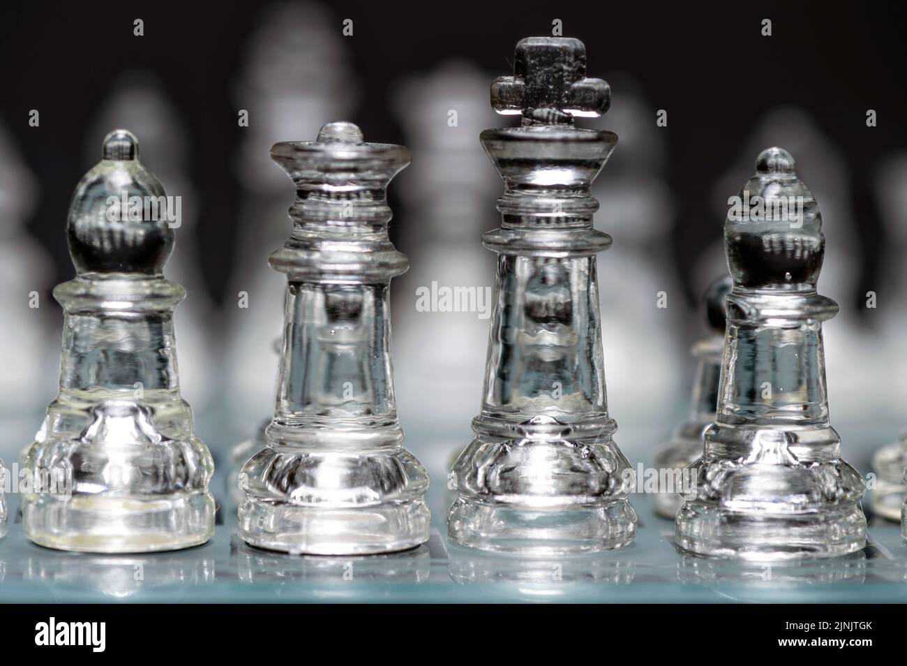 verre transparent, pièces d'échecs transparentes sur un damier, mise au point sélective, gros plan, isolé sur le noir Banque D'Images