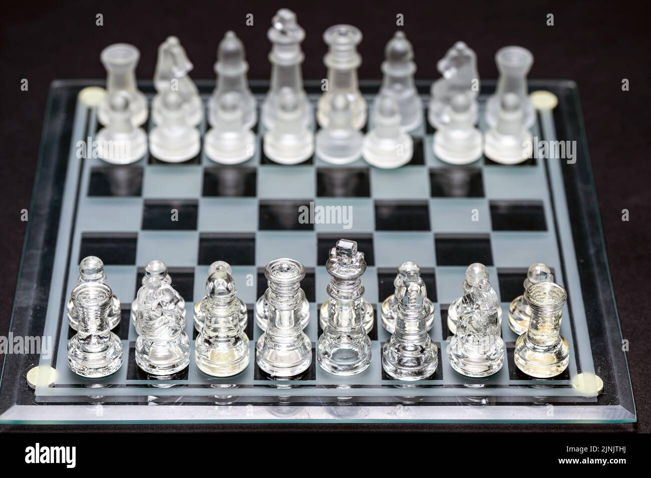 Ensemble de pièces d'échecs en verre transparent sur noir, mise au point sélective, espace de copie Banque D'Images