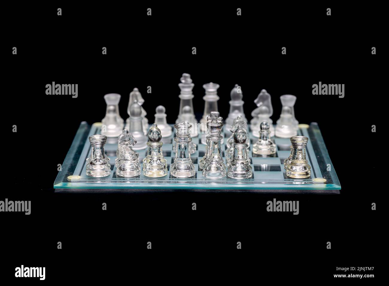 Ensemble de pièces d'échecs en verre transparent sur noir, mise au point sélective, espace de copie Banque D'Images