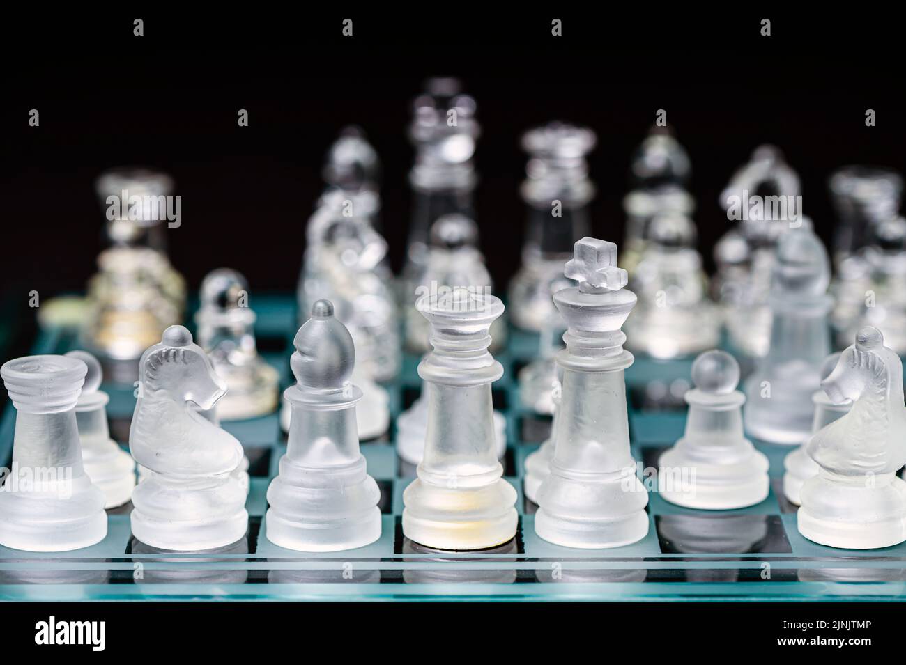 verre transparent, pièces d'échecs transparentes sur un damier, mise au point sélective, gros plan, isolé sur le noir Banque D'Images