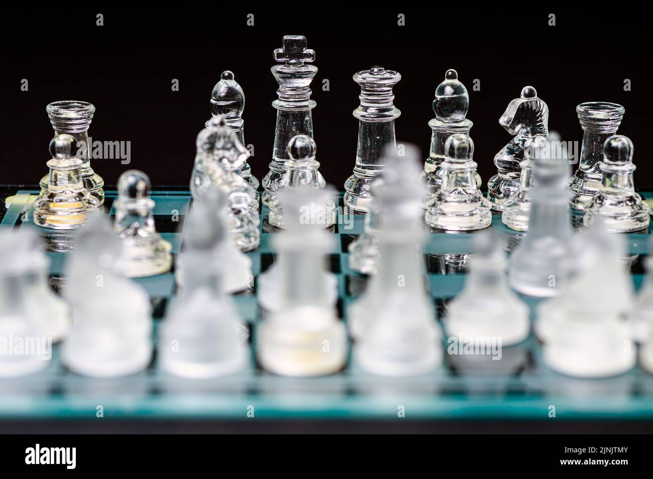 verre transparent, pièces d'échecs transparentes sur un damier, mise au point sélective, gros plan, isolé sur le noir Banque D'Images