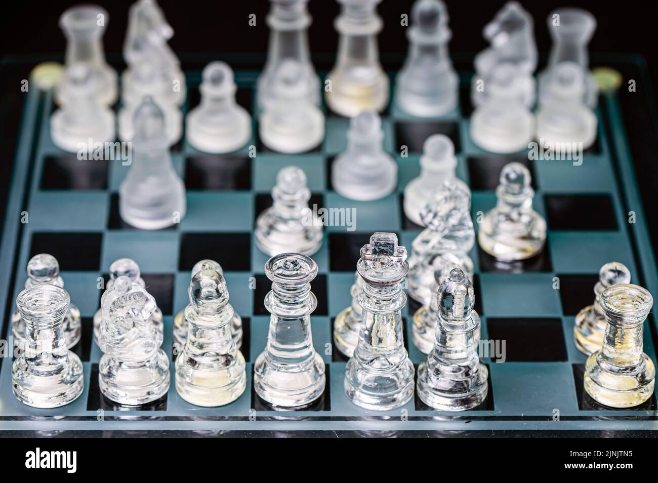 verre transparent, pièces d'échecs transparentes sur un damier, mise au point sélective, gros plan, isolé sur le noir Banque D'Images