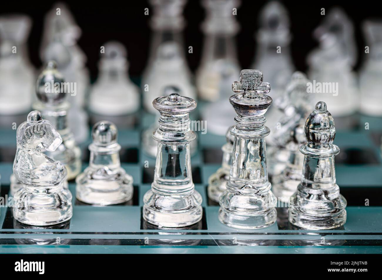 verre transparent, pièces d'échecs transparentes sur un damier, mise au point sélective, gros plan, isolé sur le noir Banque D'Images