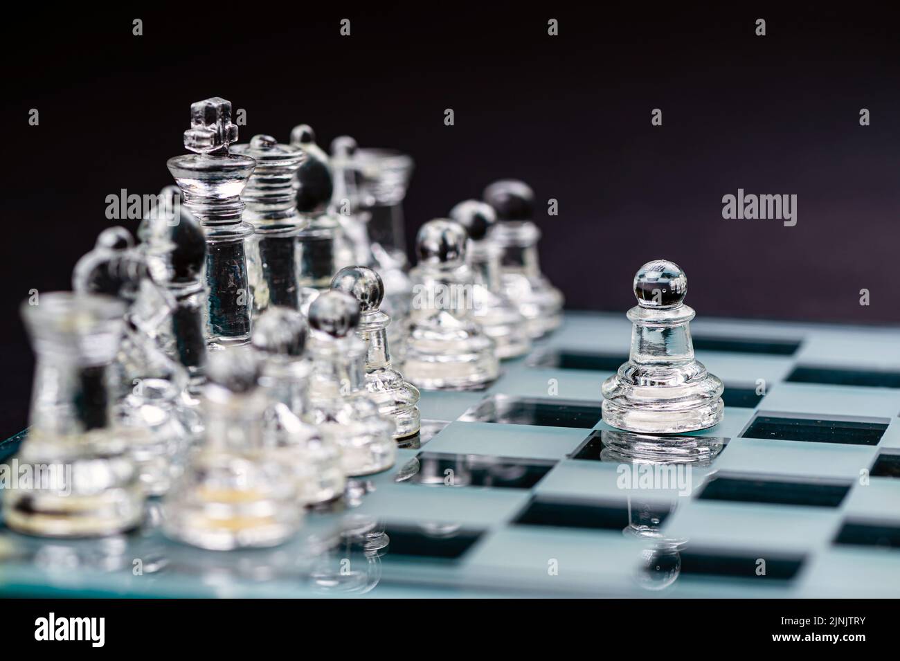 échecs en verre transparent sur fond sombre, mise au point sélective sur la pièce de pion, gros plan Banque D'Images