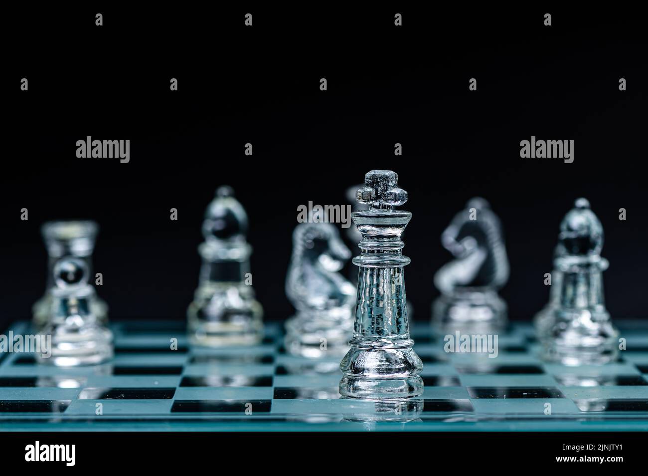 Jeu de plateau d'échecs en verre dans fond noir, focus sélectif sur King, leadership, concept gagnant Banque D'Images