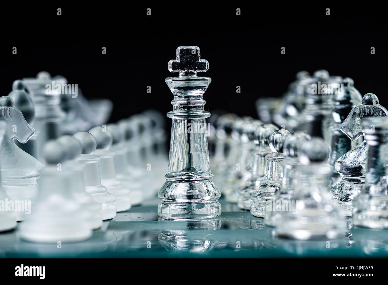 Pièces d'échecs en verre transparent sur fond sombre. Leadership, confrontation et concept de stratégie Banque D'Images