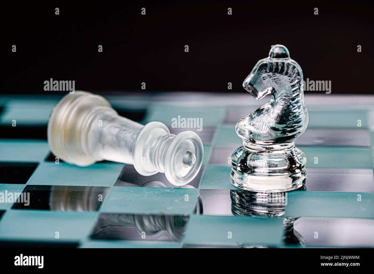 jeu d'échecs en verre transparent sur fond sombre, mise au point sélective sur la pièce de chevalier, gros plan Banque D'Images