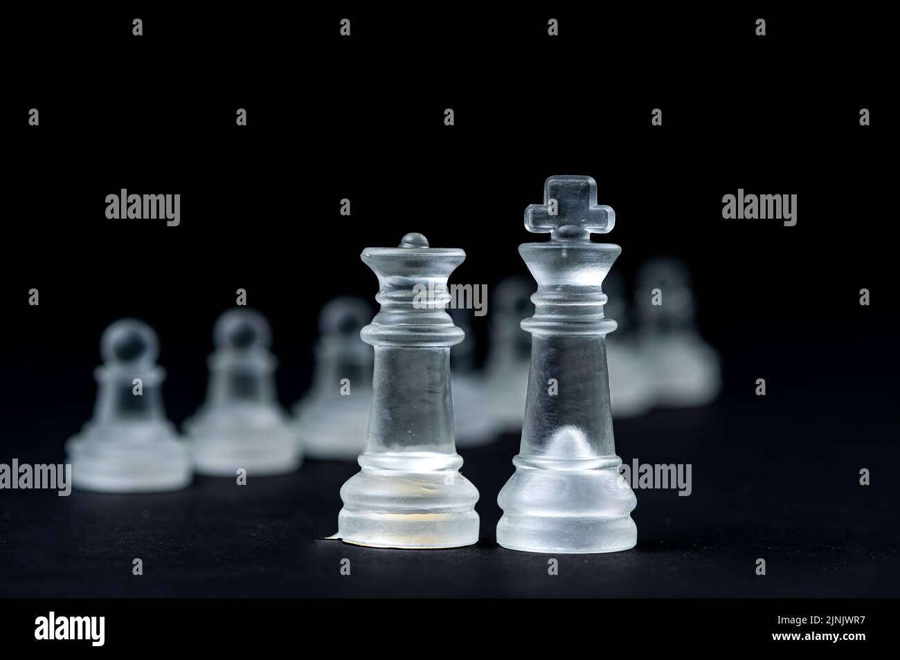 jeu d'échecs en verre transparent sur fond noir, mise au point sélective sur les pièces du roi et de la reine, gros plan Banque D'Images