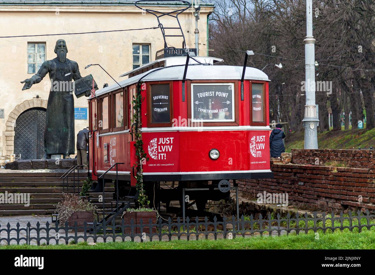 Ukraine, Lviv 21 décembre 2019 : extérieur d'un café un vieux tramway rouge sur fond du monument d'Ivan Fedorov à Lviv Banque D'Images