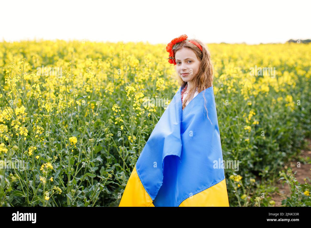 Priez pour l'Ukraine. Enfant avec drapeau ukrainien dans champ de colza. Fille tenant le drapeau national priant pour la paix. Banque D'Images