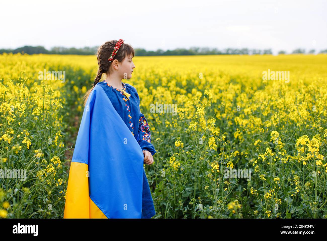 Priez pour l'Ukraine. Enfant avec drapeau ukrainien dans champ de colza. Fille tenant le drapeau national dans sa main. Banque D'Images