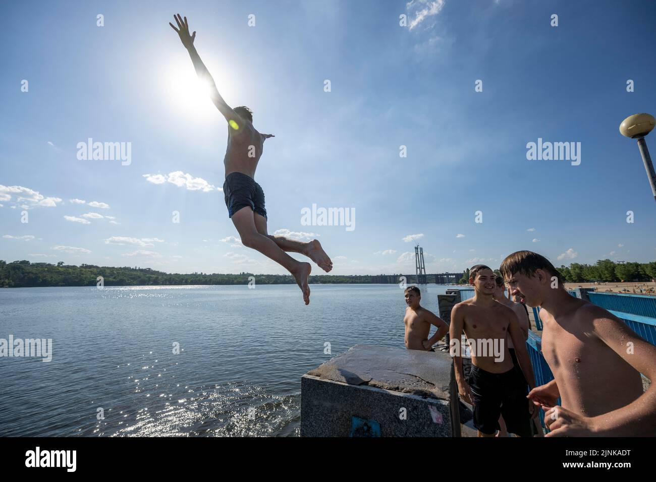La photo montre des adolescents qui s'amusent en sautant sur un quai dans la rivière Dnipro à Zaporizhzhia en Ukraine Banque D'Images