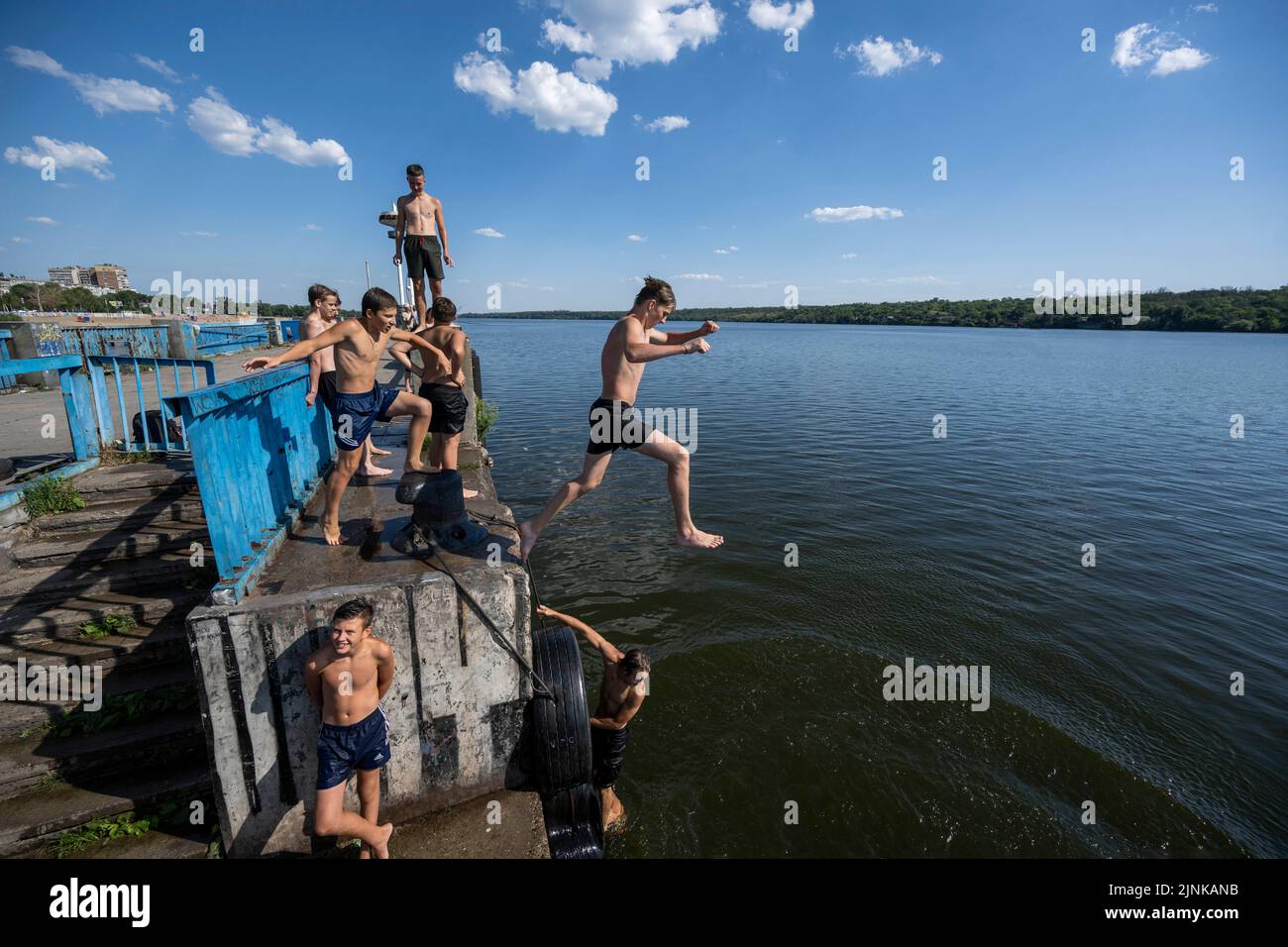 La photo montre des adolescents qui s'amusent en sautant sur un quai dans la rivière Dnipro à Zaporizhzhia en Ukraine Banque D'Images