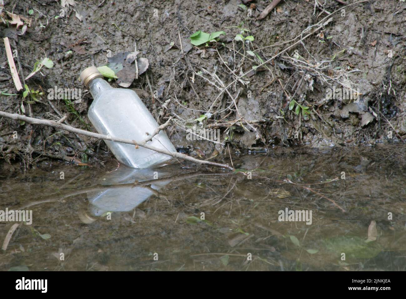 Une bouteille d'alcool innégligemment rejetée se trouve sur le côté d'une banque de Muddy creek dans le comté de Macomb, Michigan, États-Unis. Banque D'Images