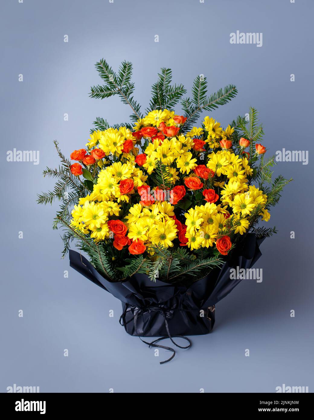 Bouquet original de petites roses roses, chrysanthèmes jaunes et brindilles d'épinette. Banque D'Images