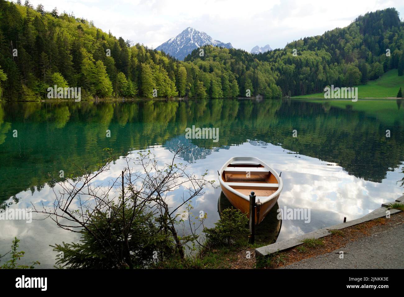 Un bateau reposant sur l'eau transparente vert émeraude du lac Alatsee à Fussen en Bavière, Allemagne Banque D'Images