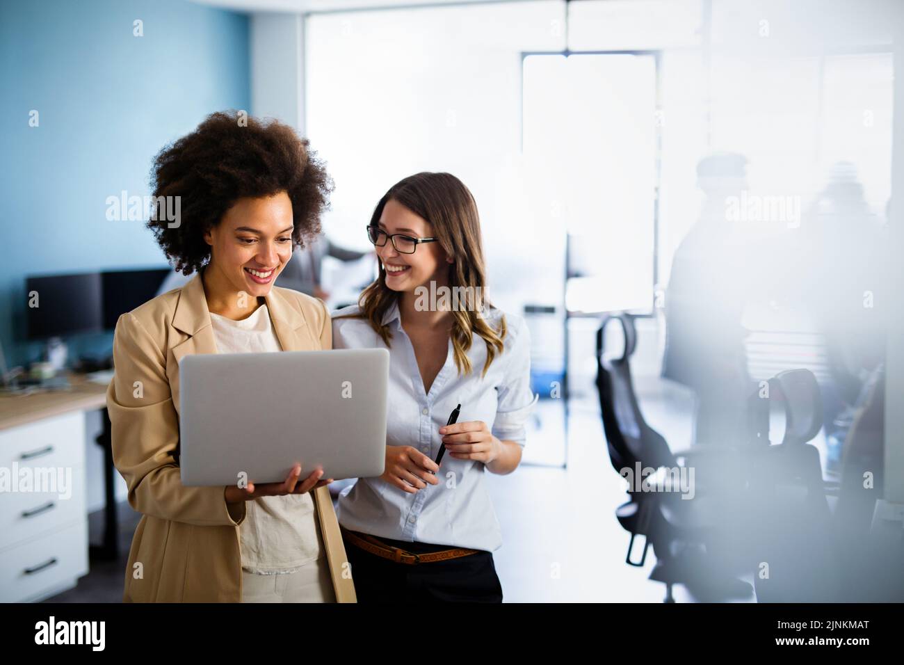 Des femmes d'affaires multiethniques heureuses travaillant ensemble en ligne sur un ordinateur portable dans un bureau d'entreprise. Banque D'Images