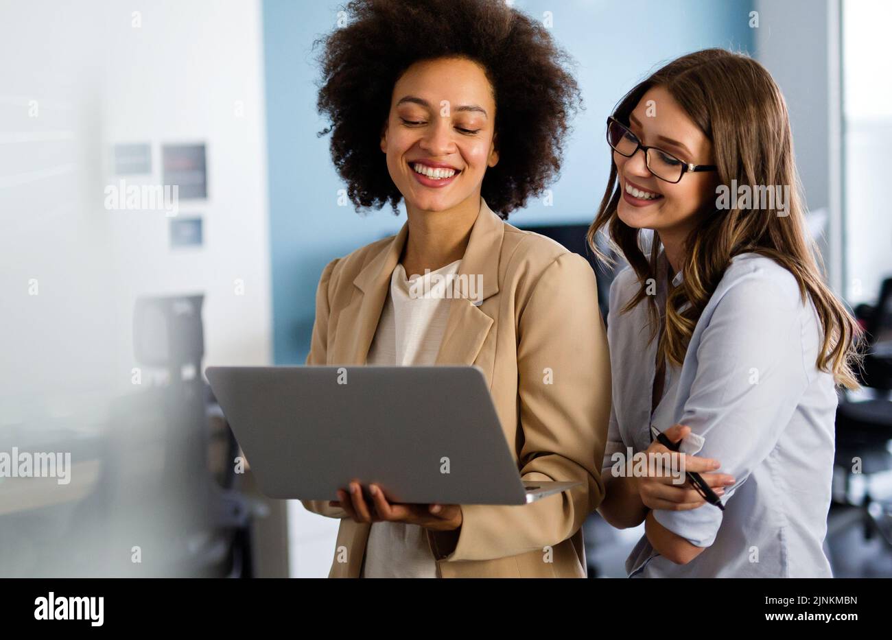 Des femmes d'affaires multiethniques heureuses travaillant ensemble en ligne sur un ordinateur portable dans un bureau d'entreprise. Banque D'Images