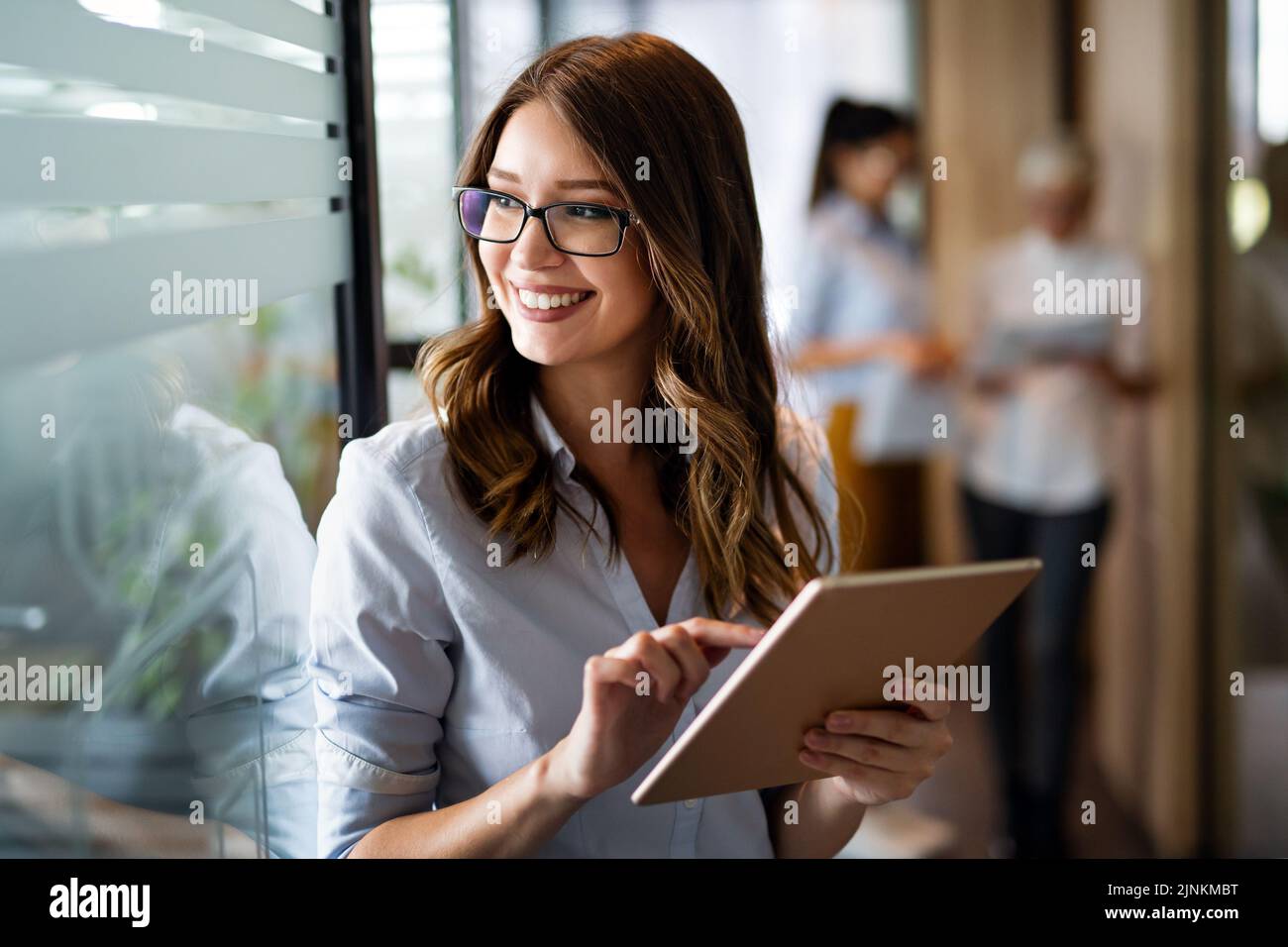 Jeune femme d'affaires heureuse travaillant avec une tablette dans un bureau d'entreprise Banque D'Images