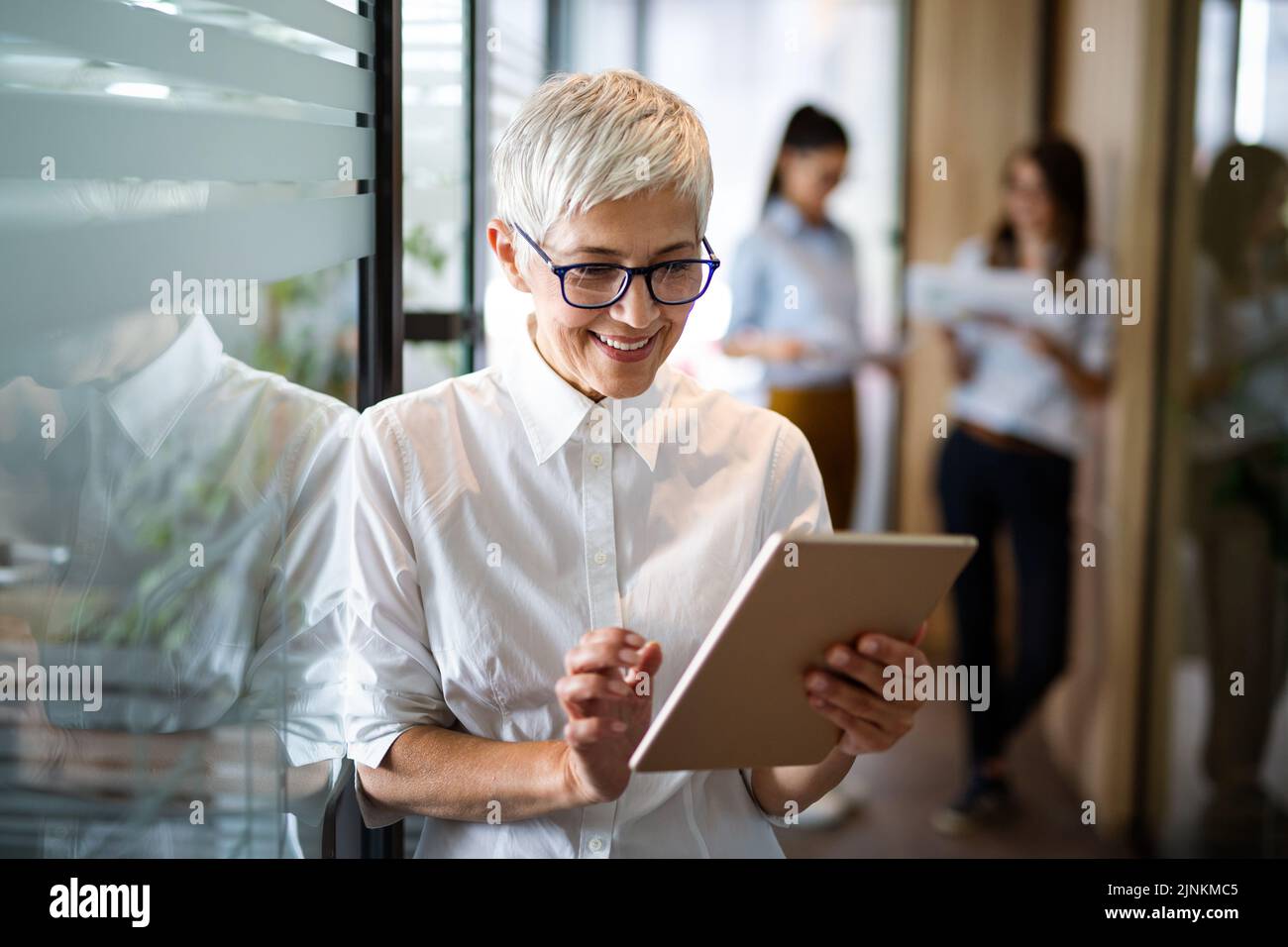 Une femme d'affaires européenne mature et confiante se tenant sur le lieu de travail. Banque D'Images