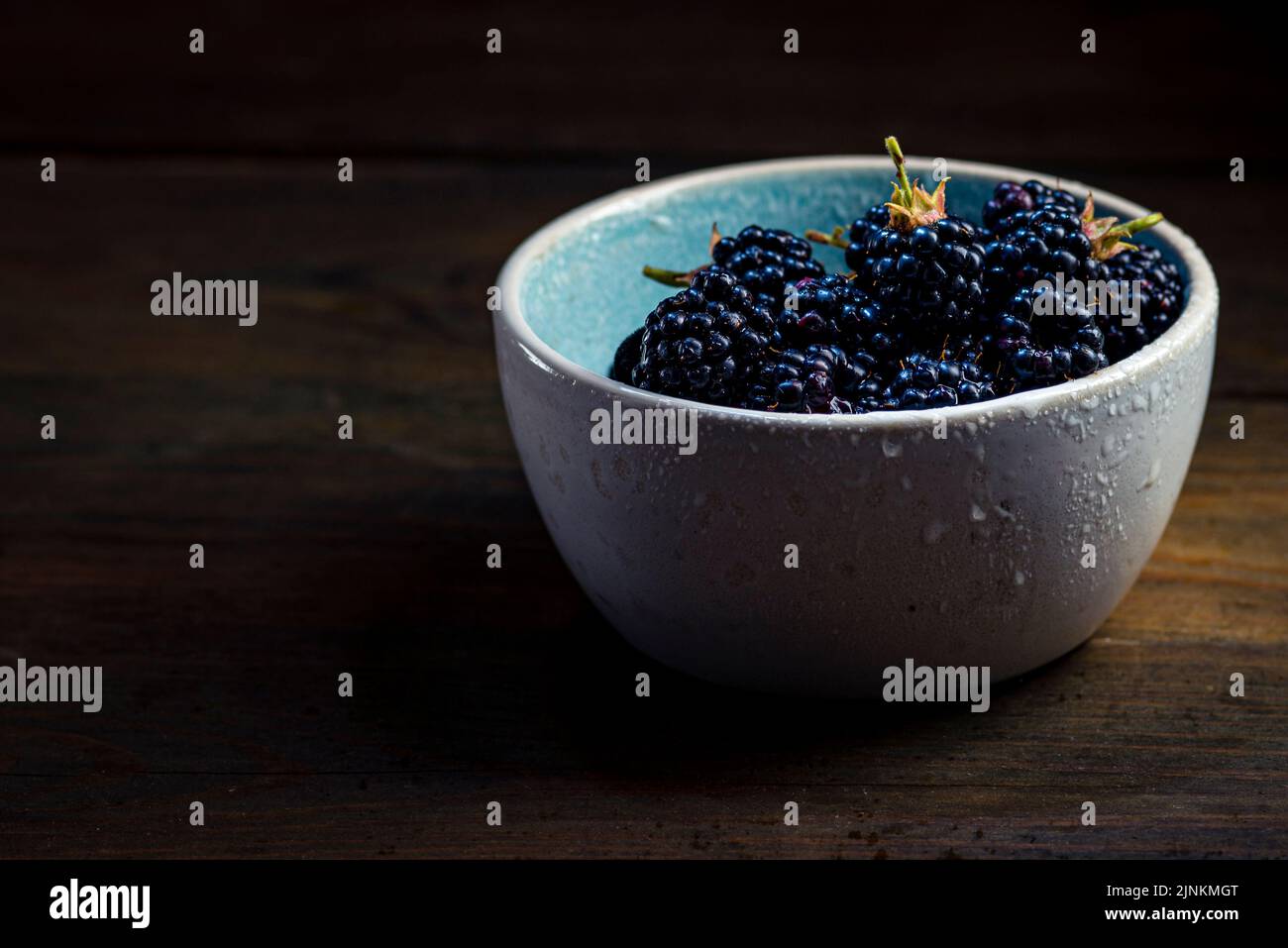 Mûres de mûre avec des feuilles dans un bol d'argile sur un fond de bois sombre photographie de nourriture, Sweet Tasty heap antioxydant bio superfood Banque D'Images