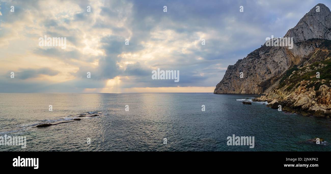 Paysage marin panoramique avec grande montagne au bord de la mer et coucher de soleil doré. Banque D'Images