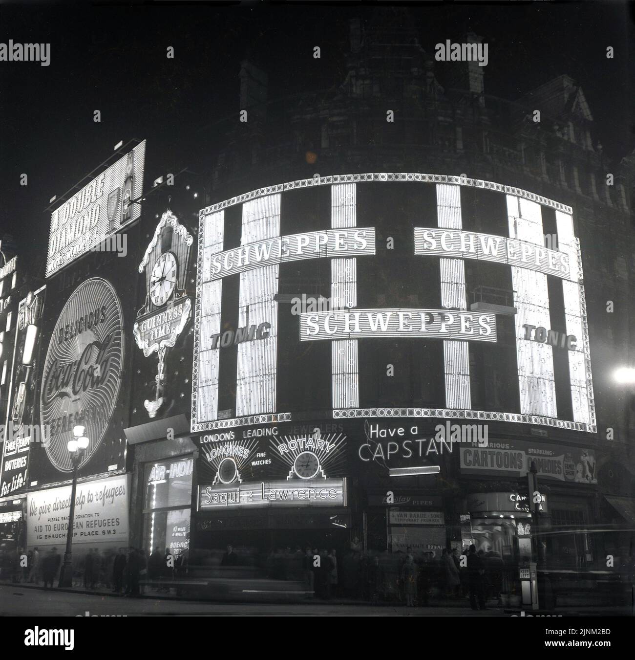 1960, historique, extérieur, Piccadilly cicrus at Night, Londres, Angleterre, Royaume-Uni. Les principales marques de boissons de l'époque, la publicité; Schweppes Tonic, Coca-cola, Double Diamond et la marque de cigarettes avec la ligne de sangle, ont un cabestan. De plus, à gauche, un panneau d'affichage pour un appel caritatif en faveur des réfugiés, "aide aux réfugiés européens". Banque D'Images