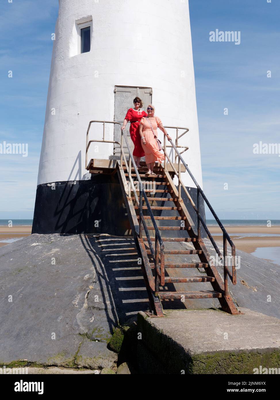Les femmes habillées avec élégance au phare de point of Ayr alias Talacre Lighthouse, un bâtiment classé Grade II situé sur la plage. Pays de Galles. Banque D'Images
