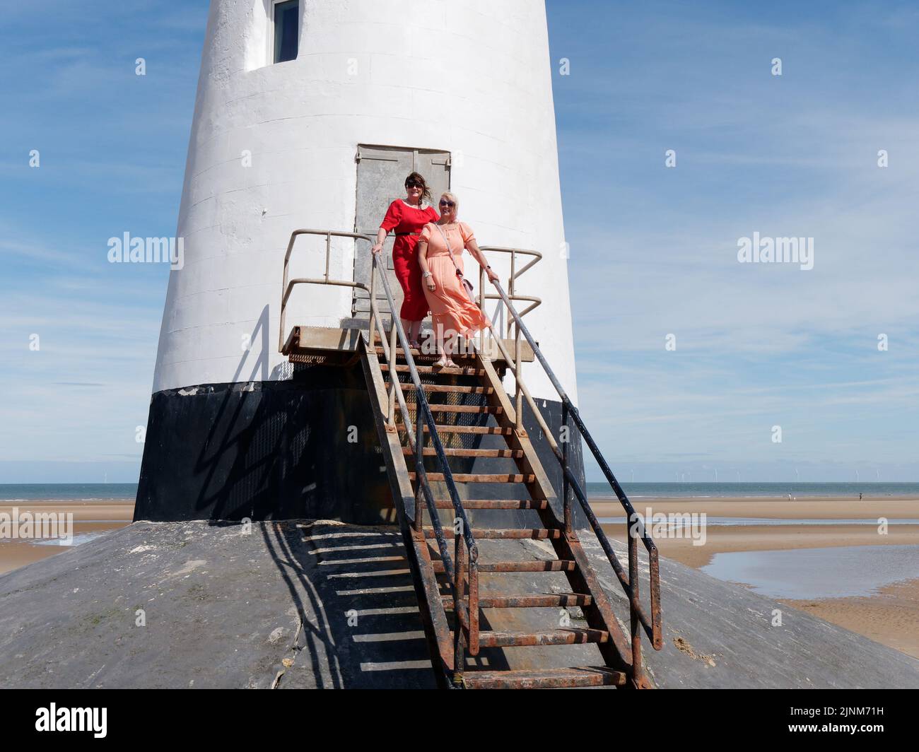 Les femmes habillées avec élégance au phare de point of Ayr alias Talacre Lighthouse, un bâtiment classé Grade II situé sur la plage. Pays de Galles. Banque D'Images