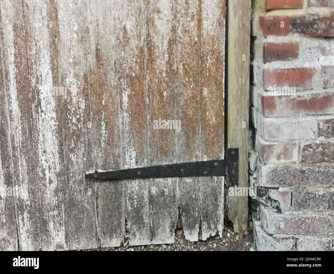 Charnière en métal noir sur l'ancienne porte de rotting avec mur en brique sur le côté Banque D'Images