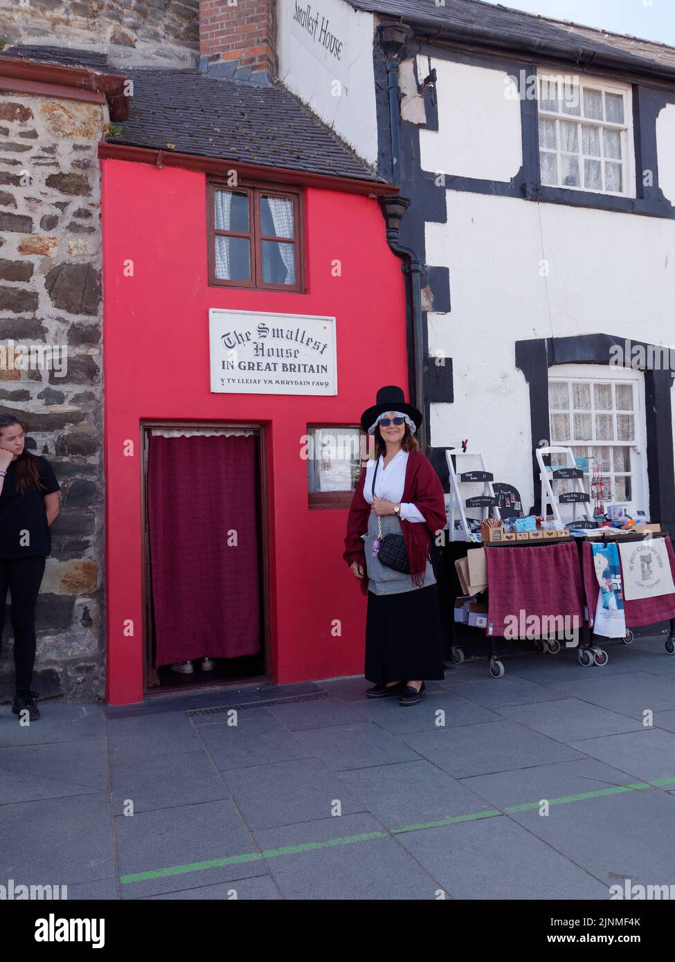 Conwy, Clwyd, pays de Galles, 07 août 2022: La dame dans un chapeau se tient à l'extérieur de la plus petite maison de Grande-Bretagne. Banque D'Images