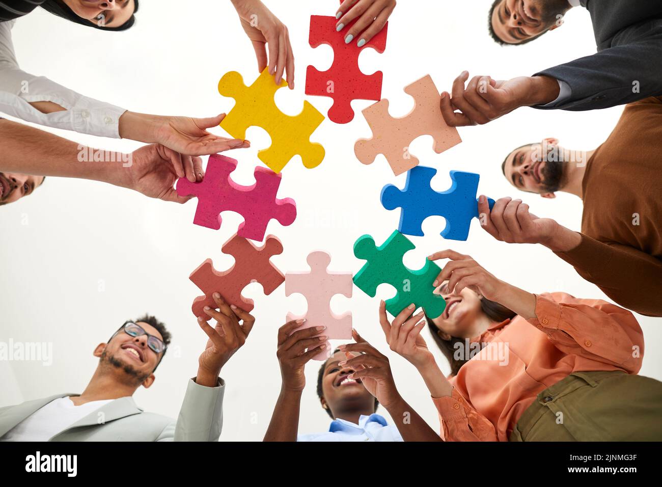 Une équipe diversifiée de jeunes gens d'affaires heureux qui relient des pièces d'un puzzle Banque D'Images