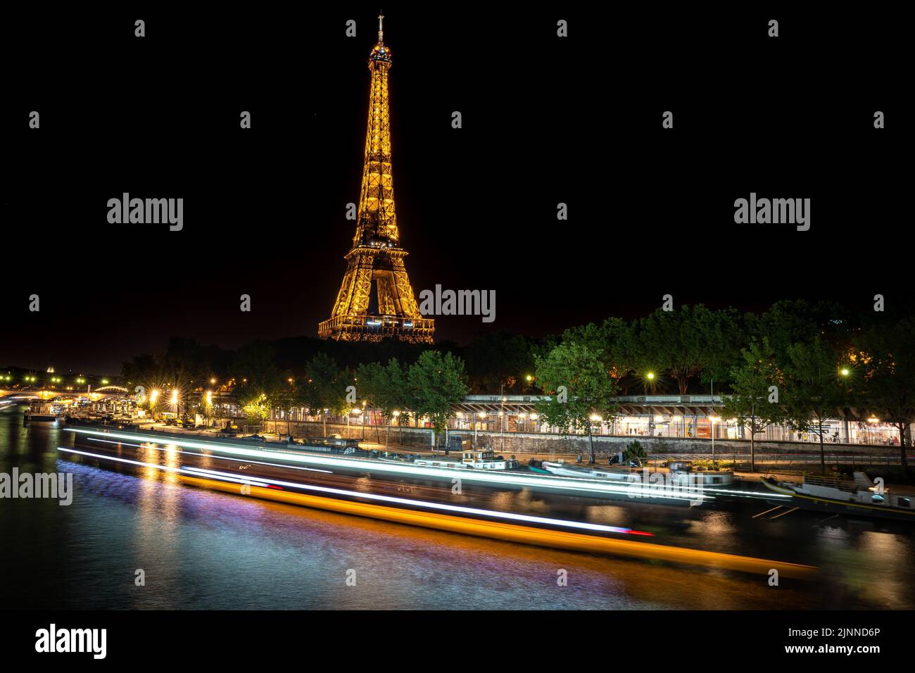 Longue exposition de la Seine la nuit avec un sentier lumineux d'un navire, Paris, France Banque D'Images
