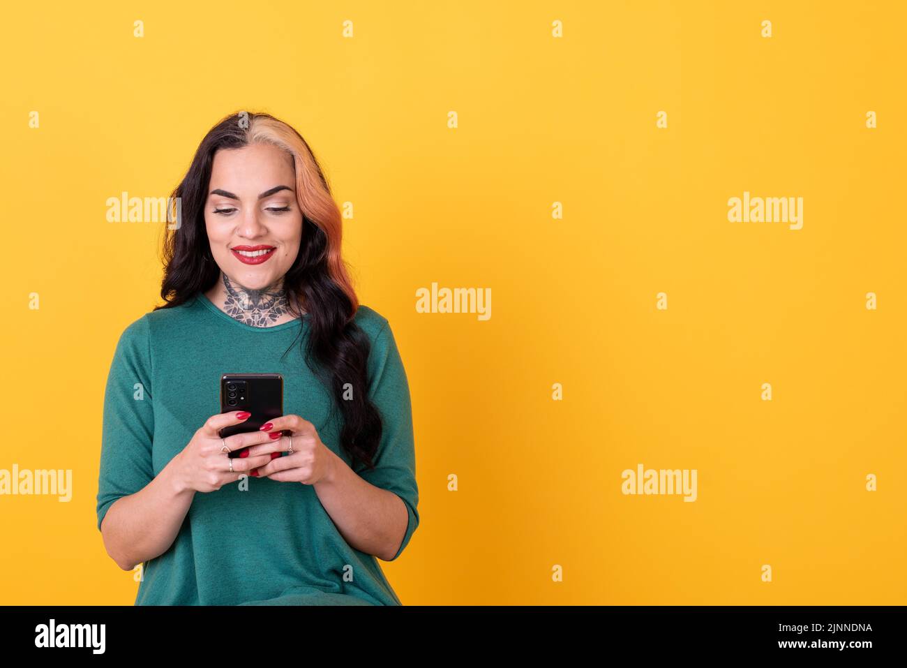 Portrait d'une femme attrayante utilisant un smartphone sur fond jaune. Copier l'espace Banque D'Images