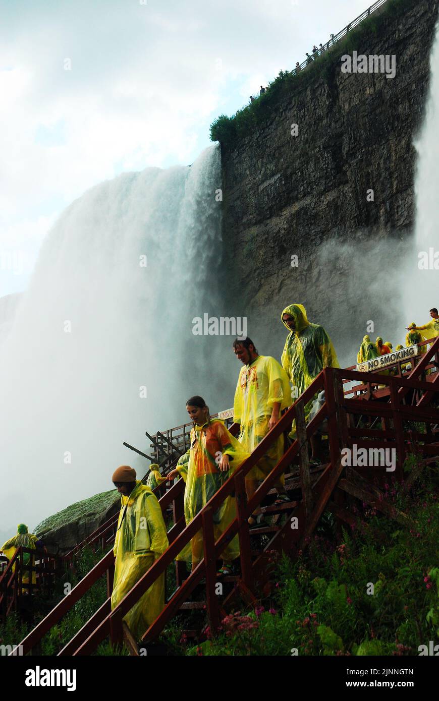 Les personnes portant des manteaux de pluie poncho jaunes descendent les escaliers de la visite Cave of the Winds qui amène les visiteurs à la base des chutes américaines du Niagara Banque D'Images