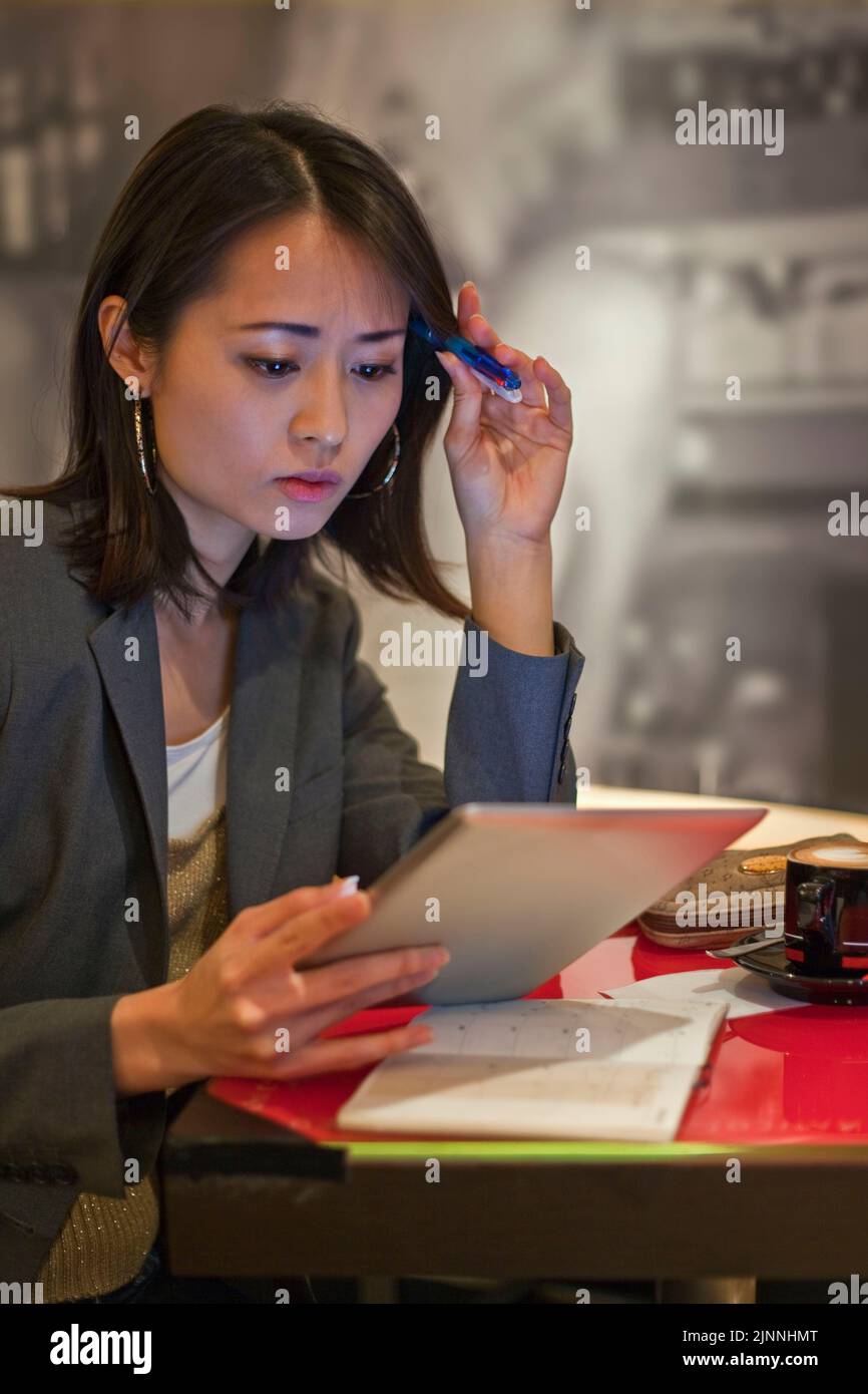 Jeune femme asiatique avec iPad et capuchino dans un café, Tokyo, Japon Banque D'Images