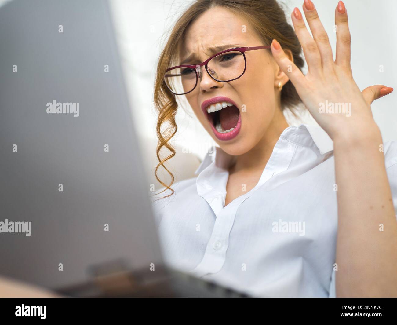 Femme hurlant et frustrée devant un écran d'ordinateur portable. Erreur fatale. Banque D'Images