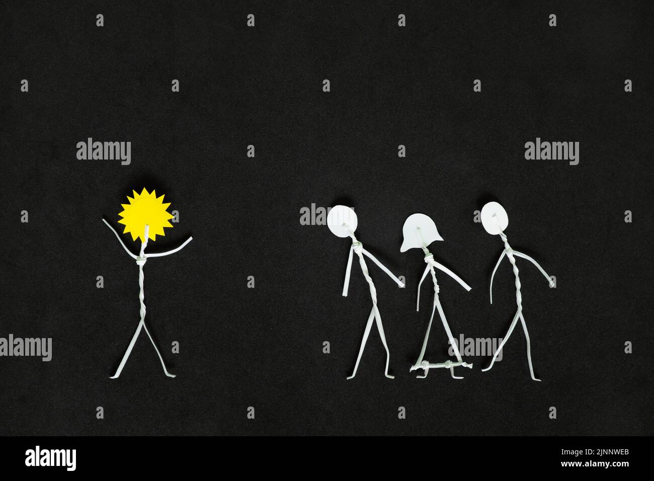 Étendre la positivité et être un rayon de soleil ou de lumière à d'autres personnes concept. L'homme colle la figure avec le soleil tandis que la tête applaudisse les autres en noir foncé Banque D'Images