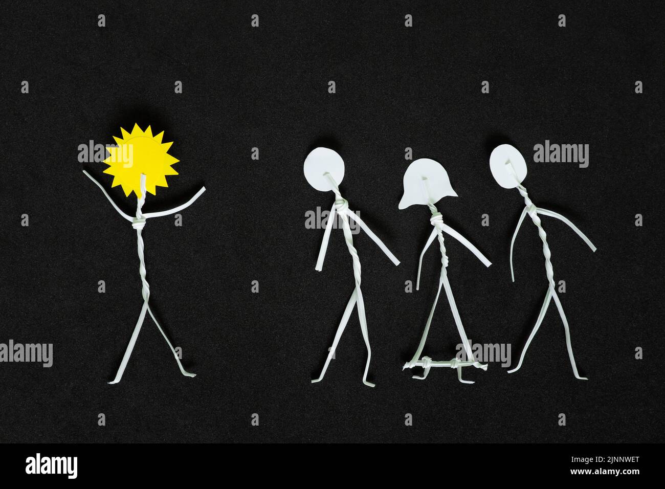 Étendre la positivité et être un rayon de soleil ou de lumière à d'autres personnes concept. L'homme colle la figure avec le soleil tandis que la tête applaudisse les autres en noir foncé Banque D'Images